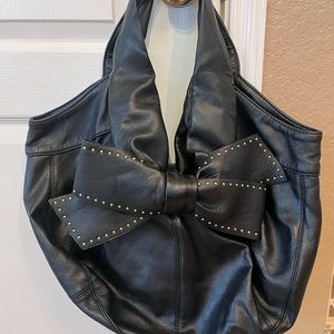 Large Betsy Johnson handbag with button closure and various zipper pockets.
